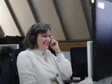 A middle aged woman sat in an office working on a computer 