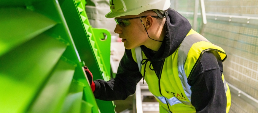 A young man wearing a hard hat and a high visibility vest