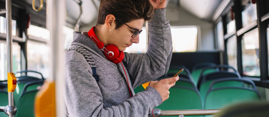 A young man on a bus holding a mobile phone