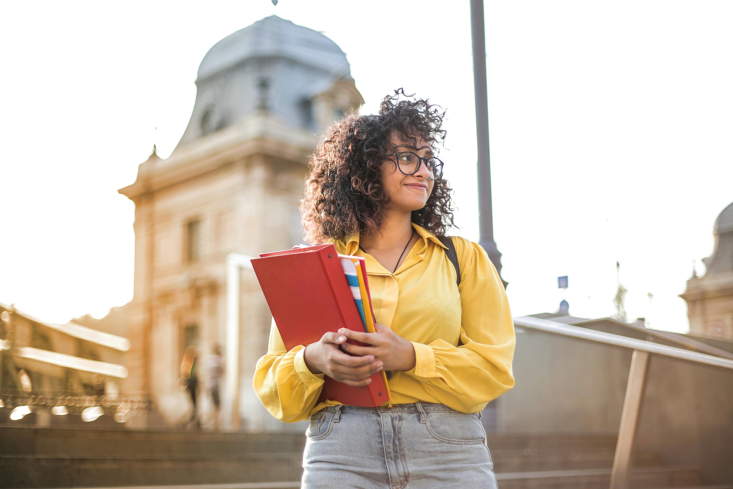A young woman holding a folder stood outside on some steps