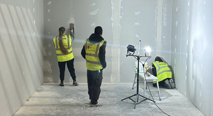 Three people preparing a room to be spray plastered