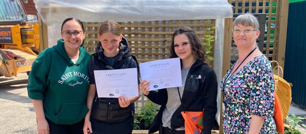 Two young people with their certificates for completing the scheme