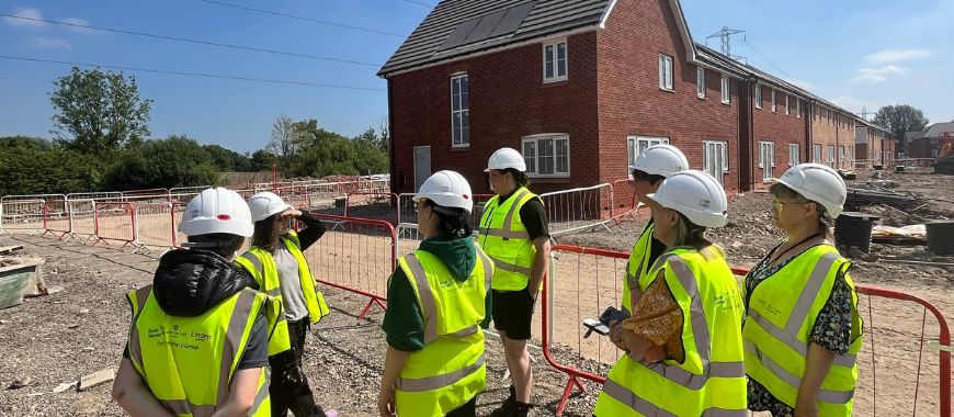 A group of people wearing high visibility vests and hard hats on a building site
