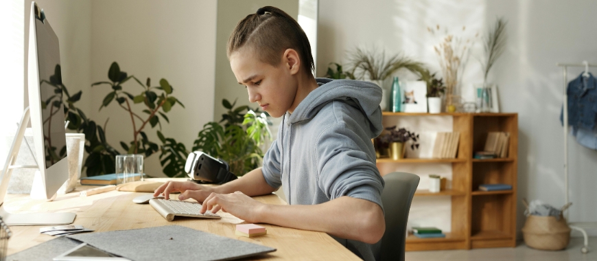 A boy sat at a desk working on a computer