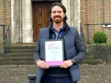 A man holding a certificate stood outside the Salford Civic Centre