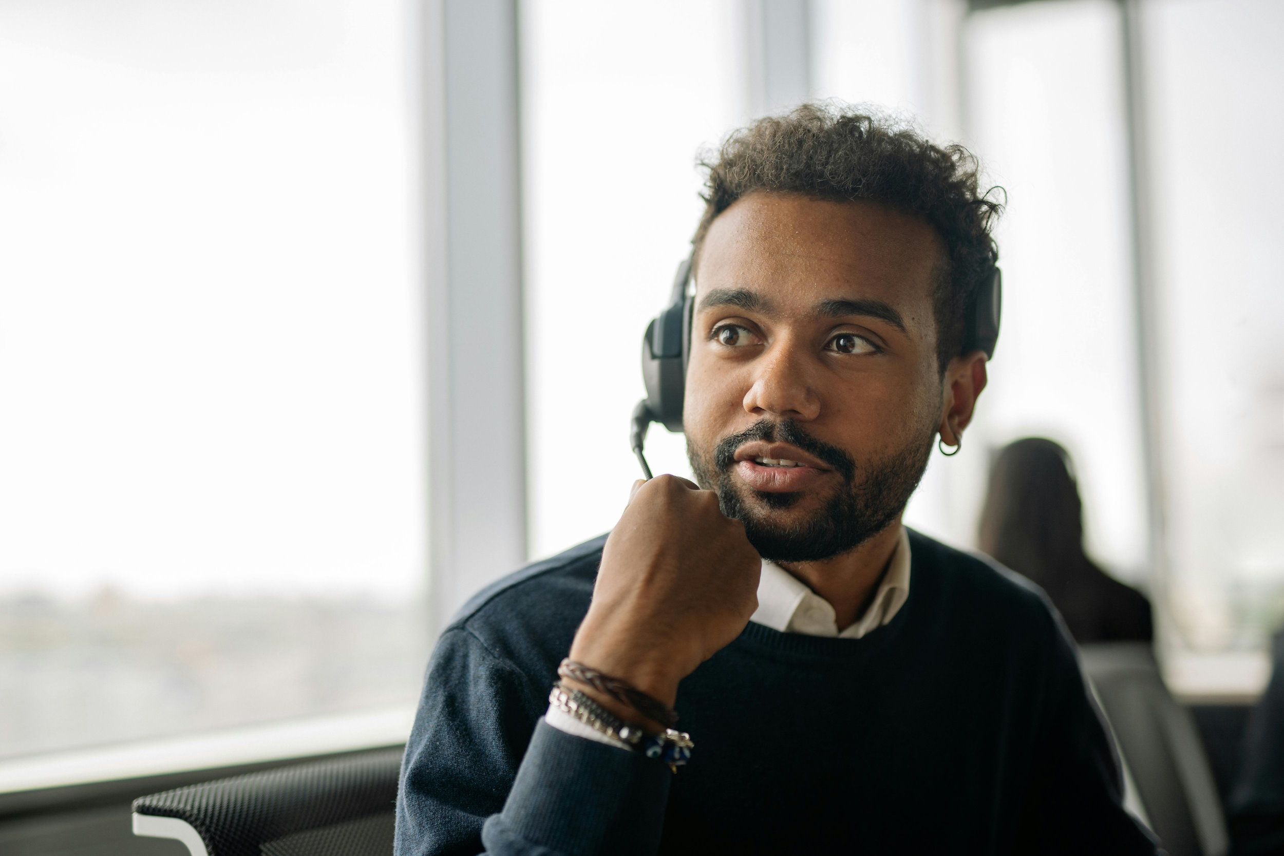 A young man sat down in an office wearing a headset